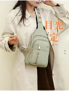 Close-up of light green PU leather crossbody bag featuring an earphone hole and gold zippers