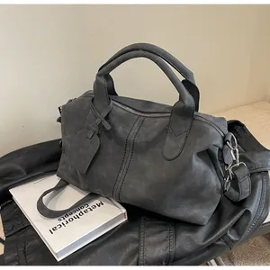 Detail einer dunkelgrauen Boston-Handtasche aus mattem Leder mit silbernen Beschlägen
