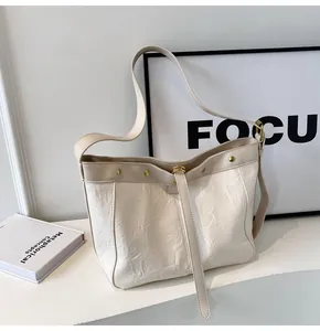 Detailed macro view of cream PU leather tote with pleated texture and gold rivet studs