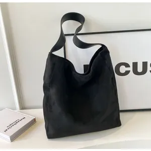 Close-up of matte black suede tote bag showing its premium texture and wide shoulder strap
