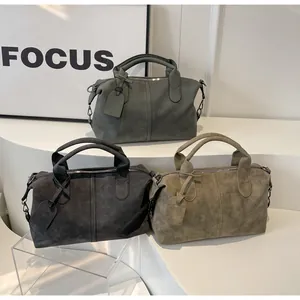 Mehrere matte Boston-Taschen in Salbeigrün, Dunkelgrau und Khaki auf einem weißen Podest