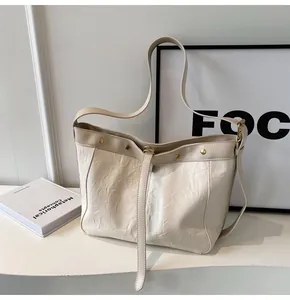 Detail of cream pleated faux leather tote bag with gold stud trim and thin shoulder strap