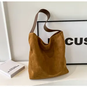 Detail der braunen Wildleder-Hobo-Tasche mit dunklem Ledergriff und großem Fassungsvermögen