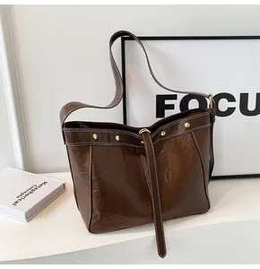 Detail of dark brown tote bag featuring white contrast stitching and gold stud accents