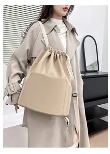 Detail of minimalist drawstring backpack in beige nylon on model in a modern interior