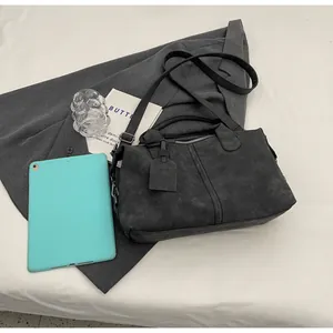 Dunkelgraue Vintage Boston Tasche auf einem Blazer mit Laptop und Glas präsentiert