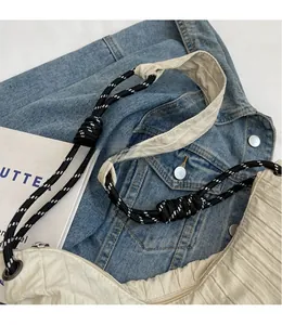 Détail d'un sac à bandoulière plissé beige avec une sangle en corde tissée noir et blanc