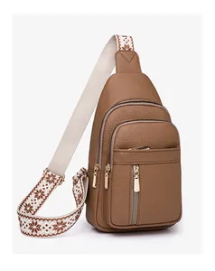 Detail of brown PU leather crossbody bag featuring gold zippers and patterned woven strap