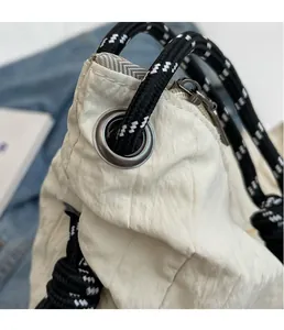 Vue détaillée du sac plissé crème avec poignées en corde tressée et œillets métalliques