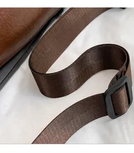 Dettaglio della tracolla regolabile in nylon e fibbia della borsa in pelle marrone