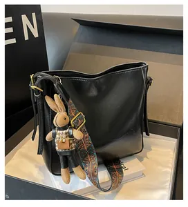 Detail van zwarte leren shopper met etnische brede riem en konijnenhanger
