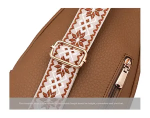 Detail of adjustable woven shoulder strap with gold metal buckle on brown leather bag