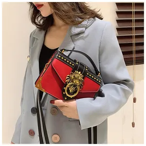 Detail of red crossbody bag with golden lion head buckle and decorative rivets