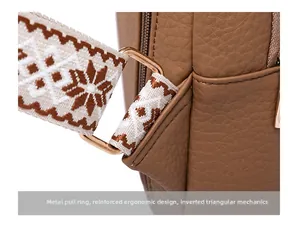 Detail of durable gold D-ring hardware and woven shoulder strap on brown PU leather bag