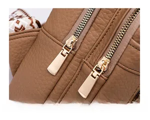 Close-up of brown litchi leather bag with gold zippers and geometric strap