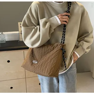 Détail d'un sac bandoulière plissé marron avec bandoulière en corde et logo en métal