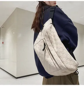 Detail of off-white woven leather chest bag featuring black zipper and nylon strap