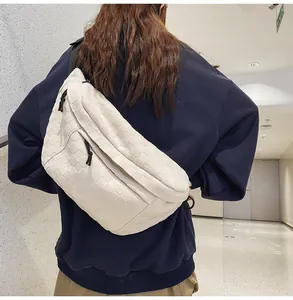 Detailed view of white woven checkerboard chest bag with black zipper on male model