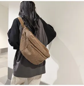Detail of brown corduroy crossbody bag texture and adjustable shoulder strap on model