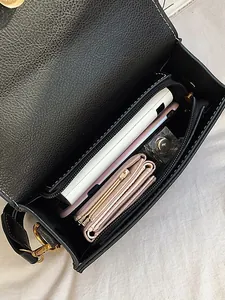 Minimalist black pebbled leather crossbody bag showing interior capacity and compartments