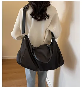 Close-up of black travel bag with adjustable strap and side pocket on a model
