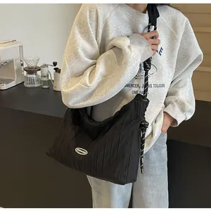 Détail d'un sac bandoulière noir plissé avec une sangle tissée bicolore noir et blanc