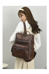 Detail view of large dark brown PU leather backpack with multi-zipper layers for travel