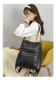Detail of black faux leather backpack with silver zippers and side pockets on a model