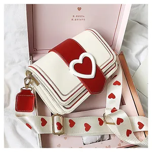 Détail d'un sac bandoulière crème avec boucle cœur dans son coffret cadeau rose
