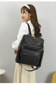Detail of black pebbled leather backpack showing multi-zipper pockets and shoulder strap