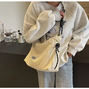 Détail d'un sac bandoulière beige plissé avec sangle en corde tissée dans un décor chic