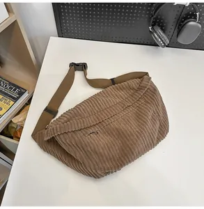 Detailed close-up of dark brown corduroy messenger bag texture with adjustable strap