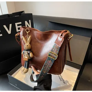 Detailweergave van bruine vintage emmertas met kleurrijke geweven riem en konijntje
