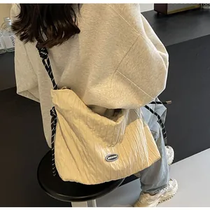 Détail du sac croissant plissé crème avec bandoulière en corde noire et blanche et logo
