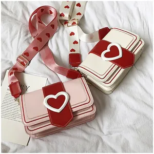 Détail de sacs à bandoulière cœur rose et blanc avec larges bretelles à motifs