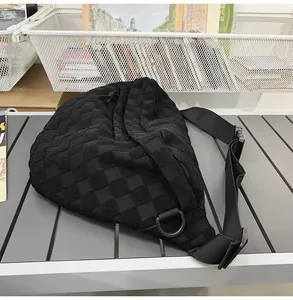 Detail of black woven nylon crossbody bag with textured grid pattern and buckle strap