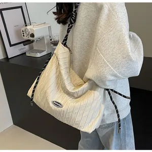 Détail du sac plissé ivoire avec bandoulière en corde tressée et logo de la marque