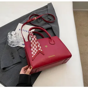 Rote Braut-Handtasche mit goldenem Herz-Detail und dekorativem Seidenschal im Detail