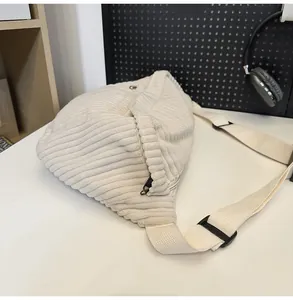 Close-up of cream corduroy chest bag featuring textured fabric and adjustable strap