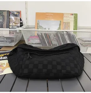 Close-up of black woven checkerboard fabric texture and knotted zipper on messenger bag