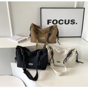 Détail de sacs à main plissés avec poignées nouées en marron, noir et beige minimalistes
