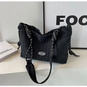 Détail du sac fourre-tout noir plissé avec anse en corde tressée et logo de marque