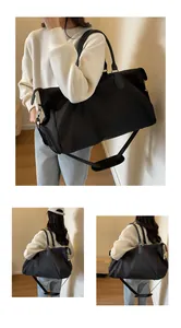 Close-up of black travel bag with dual zippers, side storage, and adjustable shoulder strap