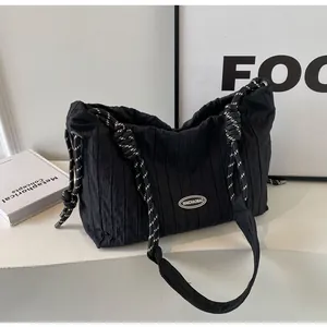 Détail d'un sac cabas noir plissé en nylon avec des anses tressées et logo en gomme