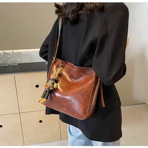 Detail van vintage bruine bucket bag met geborduurde riem en geweven konijnhanger