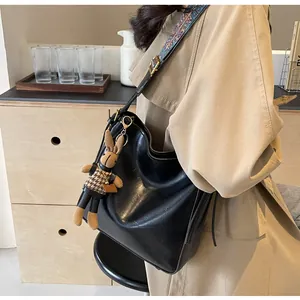 Detail van retro zwarte bucket bag met etnische schouderband en pluche konijn hanger
