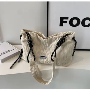 Détail du sac cabas plissé beige avec poignées en corde tressée noire et blanche à nœuds