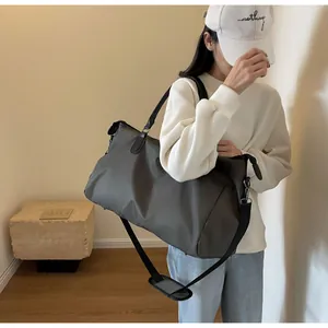 Side view of a large dark grey travel bag worn by a model with a shoulder strap