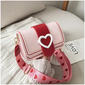 Dettaglio borsa a tracolla rosa con fibbia a cuore rosso e tracolla larga con cuori