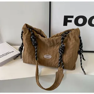 Détail d'un cabas plissé marron avec anses en corde tressée et écusson de marque chic